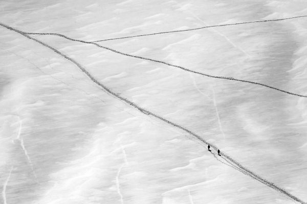 Two climbers walking on Col du Midi with tracks near Aiguille du Midi in Mont Blanc massif in black and white